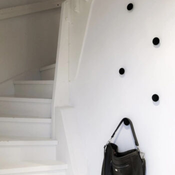 Hallway, staircase entrance. Black handbag hanging from handles